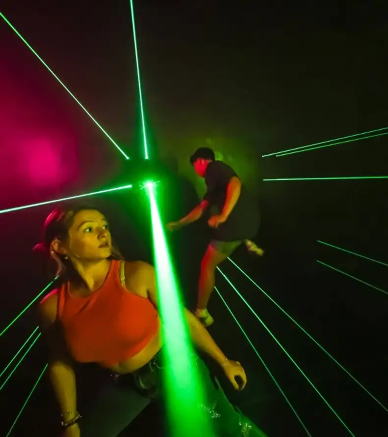 A high-tech commercial Laser Maze Game room with players dodging green beams, offering an intense immersive experience similar to the popular Activate Game laser challenge