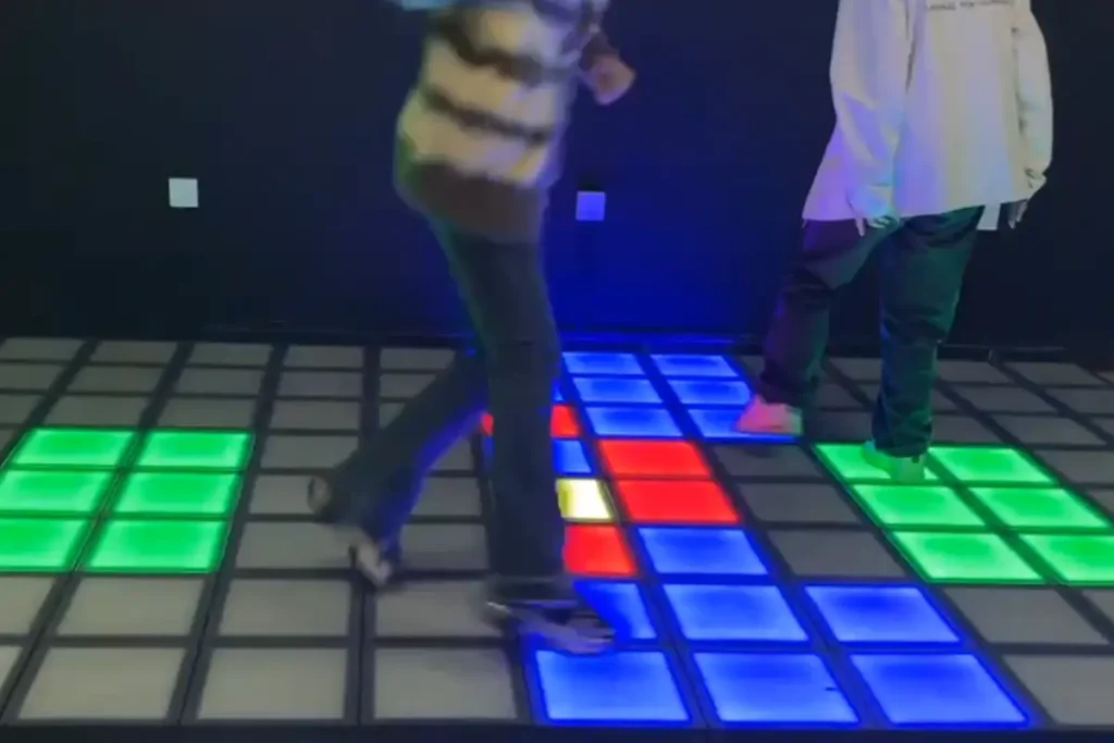 Close-up of a player's foot interacting with a capacitive sensing LED floor tile, highlighting zero-latency response.