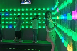 Commercial interactive LED climbing wall with blue and red glowing holds in a modern family entertainment center.