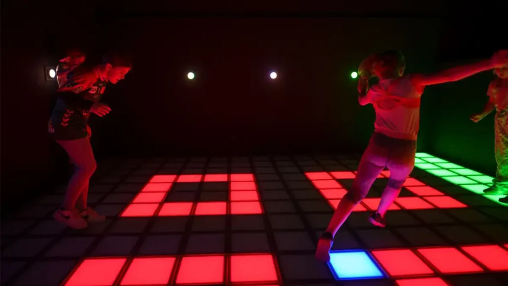 players jumping and reacting on an interactive LED floor game with colorful light tiles