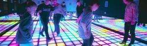 interactive pixel floor game with LED tiles and players stepping on illuminated grid