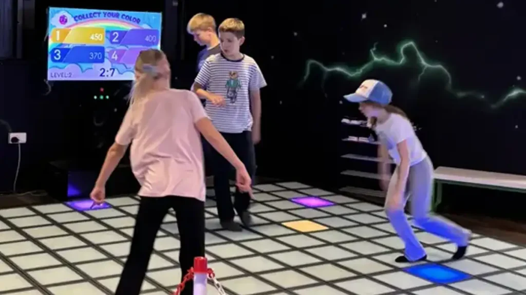 Best Interactive Attractions for FEC Venues (2026 Guide) 3 Two players competing on colorful LED grid floor inside a commercial active gaming room showing FEC attractions in operation