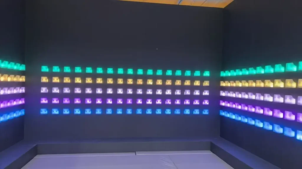 Active Gaming Room vs Activate Games Franchise: What FEC Operators Should Know (2026) 4 Commercial push button game wall showing rows of illuminated LED buttons in cyan yellow purple and blue colors installed inside an active gaming room challenge room