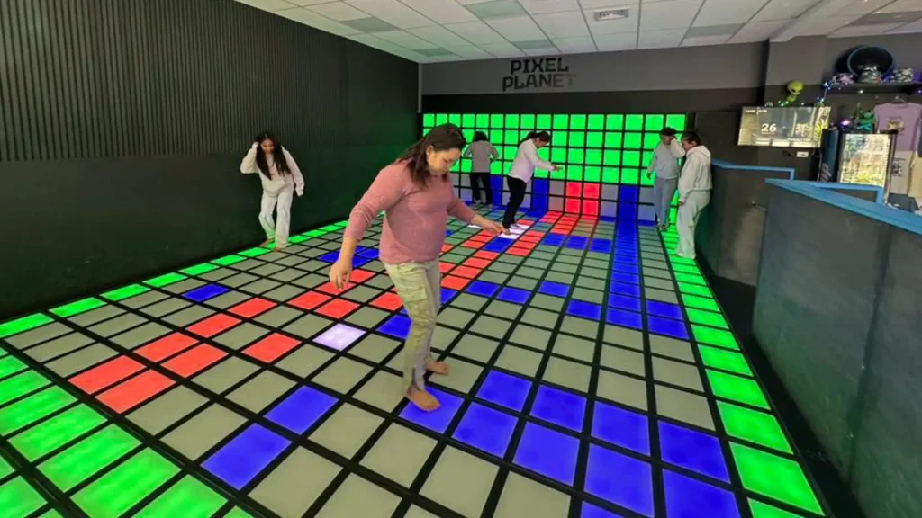 Active Gaming Room vs Activate Games Franchise: What FEC Operators Should Know (2026) 1 Multiple players stepping on red green and blue LED floor tiles inside a real active gaming room installation showing commercial venue scale for FEC operators