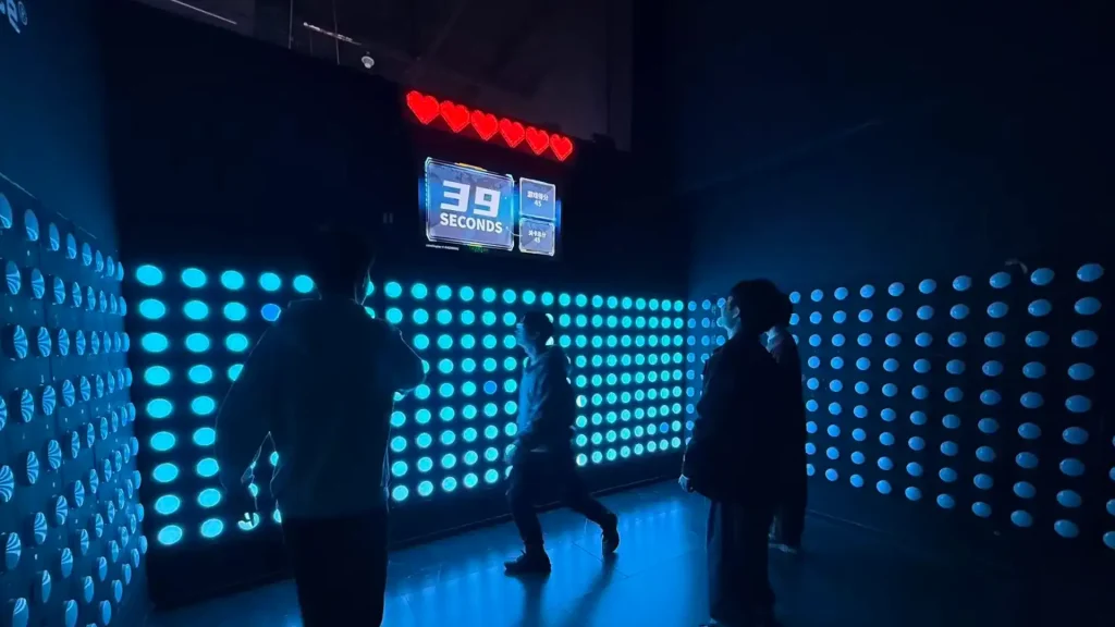 Push Button Game Wall: Commercial Reaction Room Guide for FECs (2026) 2 A group of players working together on a push button game wall reaction challenge inside an active gaming venue