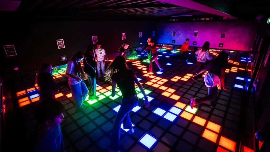 Players safely competing on commercial LED floor inside active gaming room showing safety design and equipment standards
