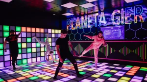 Players jumping across an illuminated interactive game floor at a commercial FEC venue
