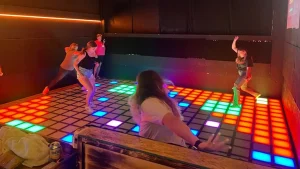 Modular interactive game floor in a family entertainment center, with a small group of players on the tiles.